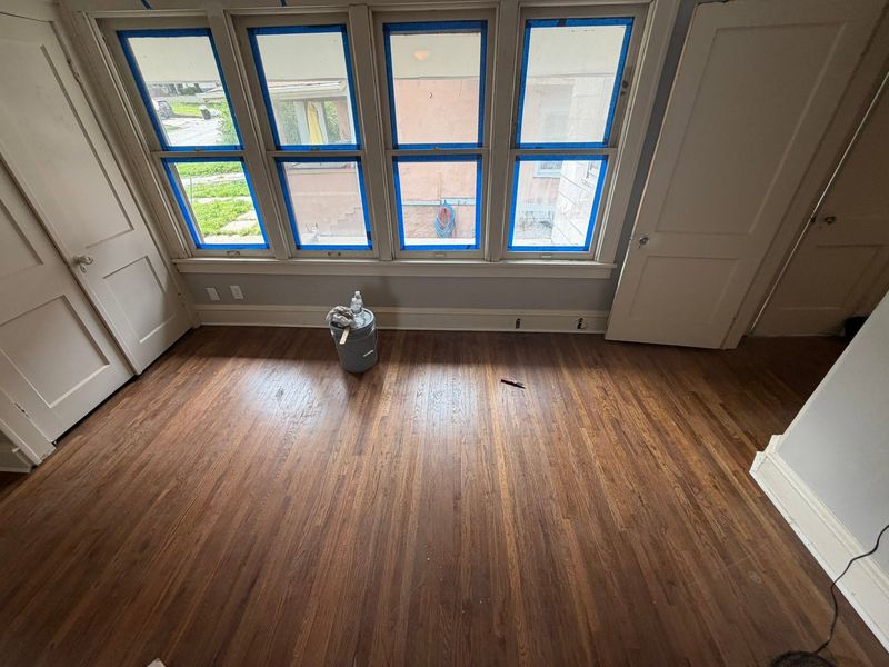 Wood floor mid-refinish in a bright room with windows
