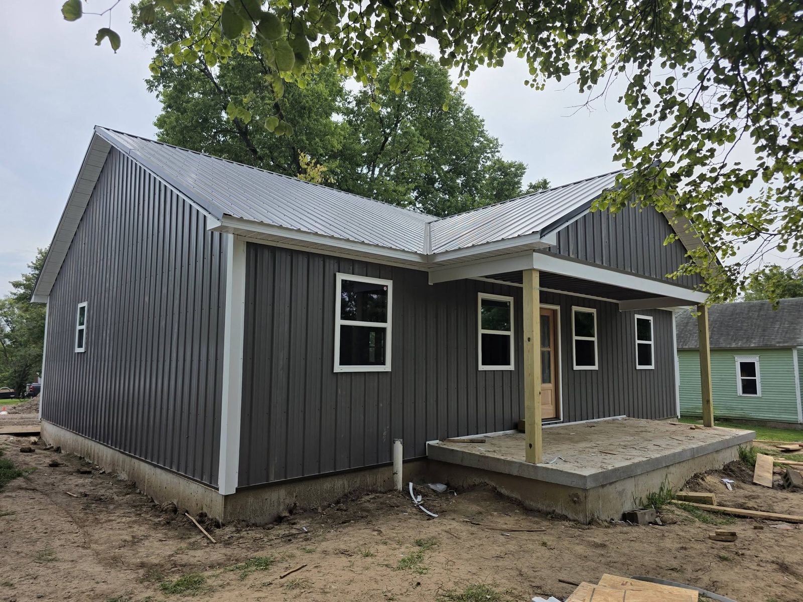 New home viewed from the front corner showing the metal roof, porch posts and concrete porch