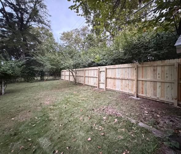 New wood privacy fence along the back of a wooded yard
