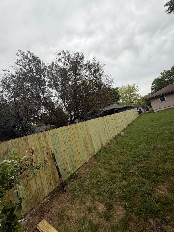 Long new wood privacy fence running down a side yard between houses